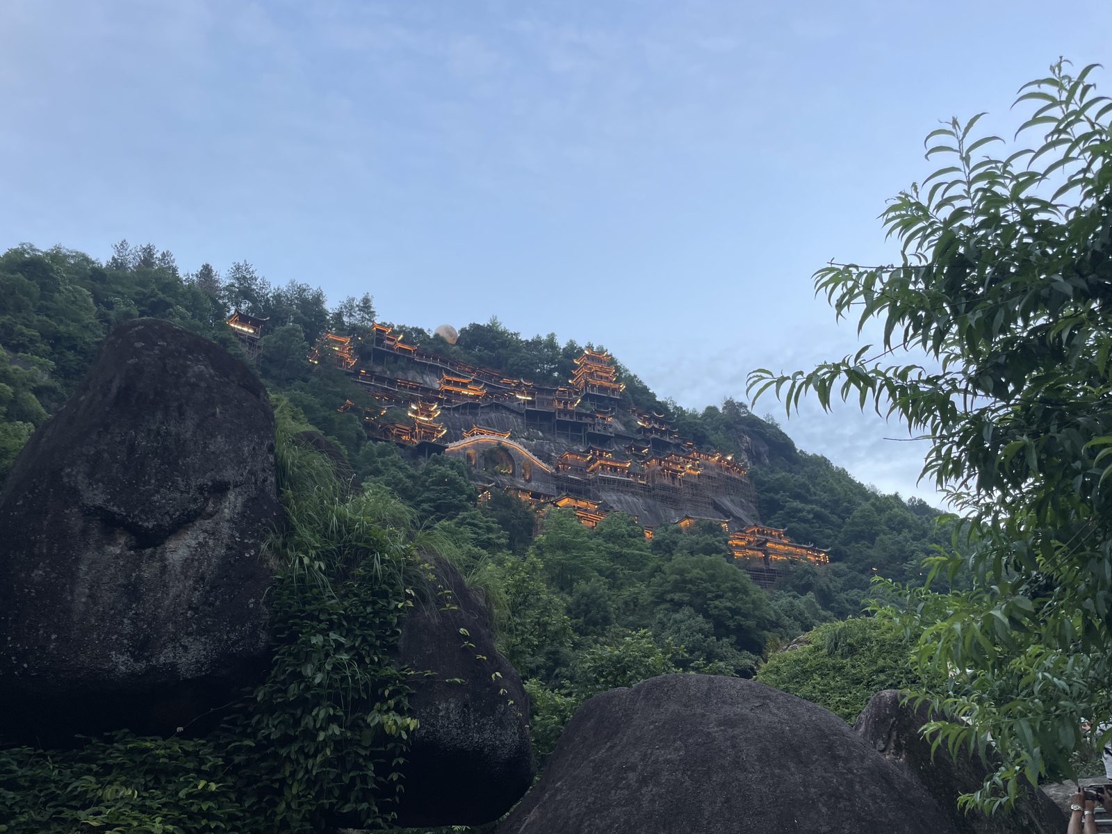 Giant boulders below the lit cliffs.